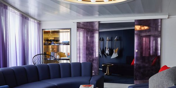 Virgin Voyages Mega RockStar Quarters showing blue couch, purple curtains, and guitars on the wall