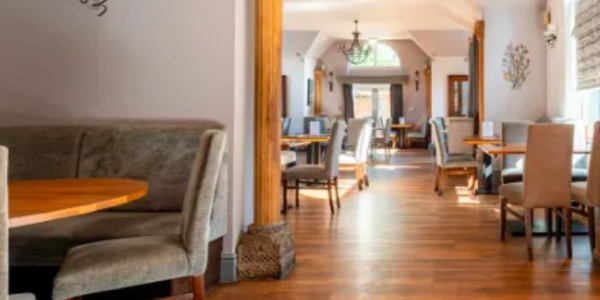Empty restaurant dining area with wooden floors and cushioned chairs.