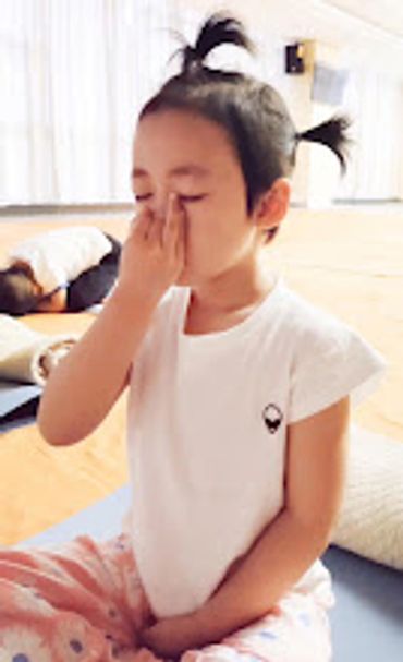 Young girl practicing a breathing exercise indoors.