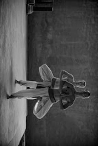 Two martial artists practicing a kata in a dimly lit dojo.