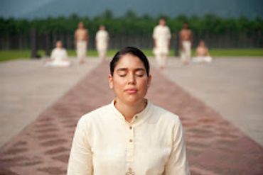 Woman meditating outdoors with eyes closed, dressed in white.