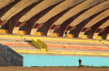"Lone Runner."  A man runs in an abandoned stadium in Havana.