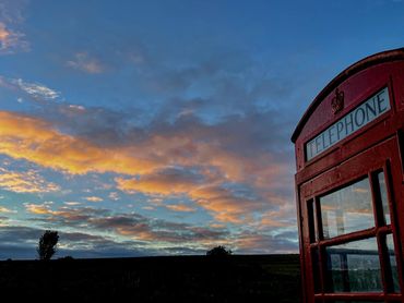 A typical red British phone booth at sunset on the moors.