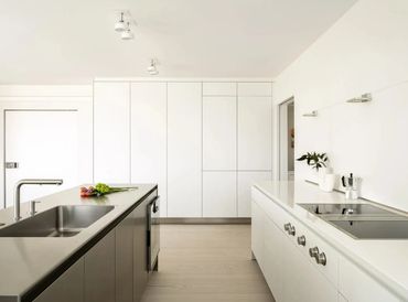 Minimalist modern kitchen with stainless steel island and white cabinetry.