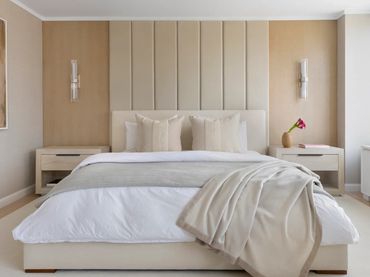 Minimalist bedroom with beige tones, a cozy bed, and matching nightstands.