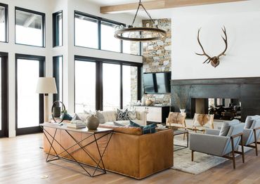 Modern rustic living room with leather sofa and stone fireplace.