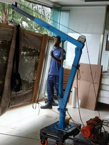 A blue hydraulic crane inside a room with a person in the background.