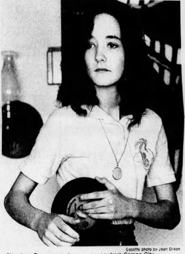 Young woman holding a record with a calm expression.