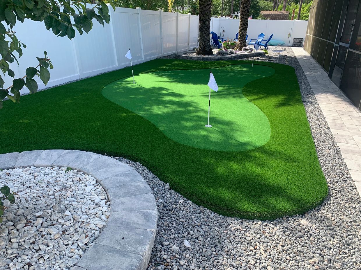 Enclosed backyard with a putting green