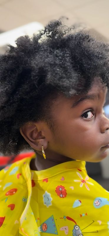 Young child with curly hair wearing a colorful yellow cape.