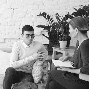 A man talking to a woman with a notebook in a cozy room.