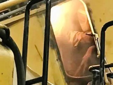 Worker welding inside a heavy machinery cabin with safety gear on.