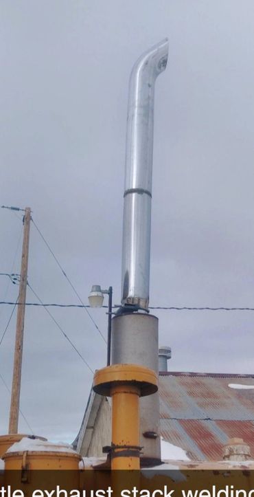Exhaust stack welding on industrial equipment with a cloudy sky.