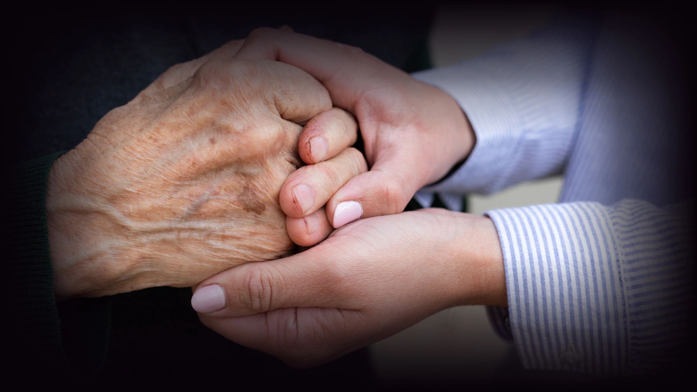 Young hands holding an elderly hand with care and warmth.