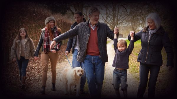 Family walking with dog and young child outdoors.