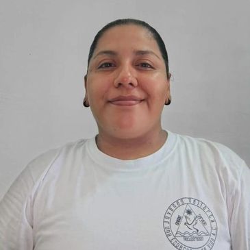 A person smiling wearing a white T-shirt with a logo.
