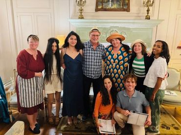A group of nine diverse people posing happily indoors with warm lighting.