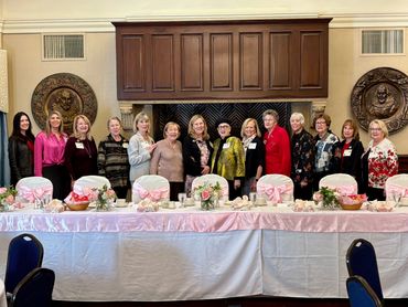 Group of women standing behind a decorated banquet table in a formal room.