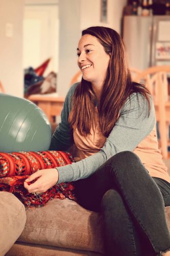Doula smiling and sitting at clients home during a prenatal with a peanut ball and rebozo 