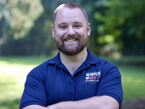 Man smiling outdoors in a blue shirt.