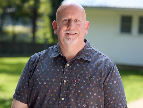 Smiling bald man outdoors in casual shirt.