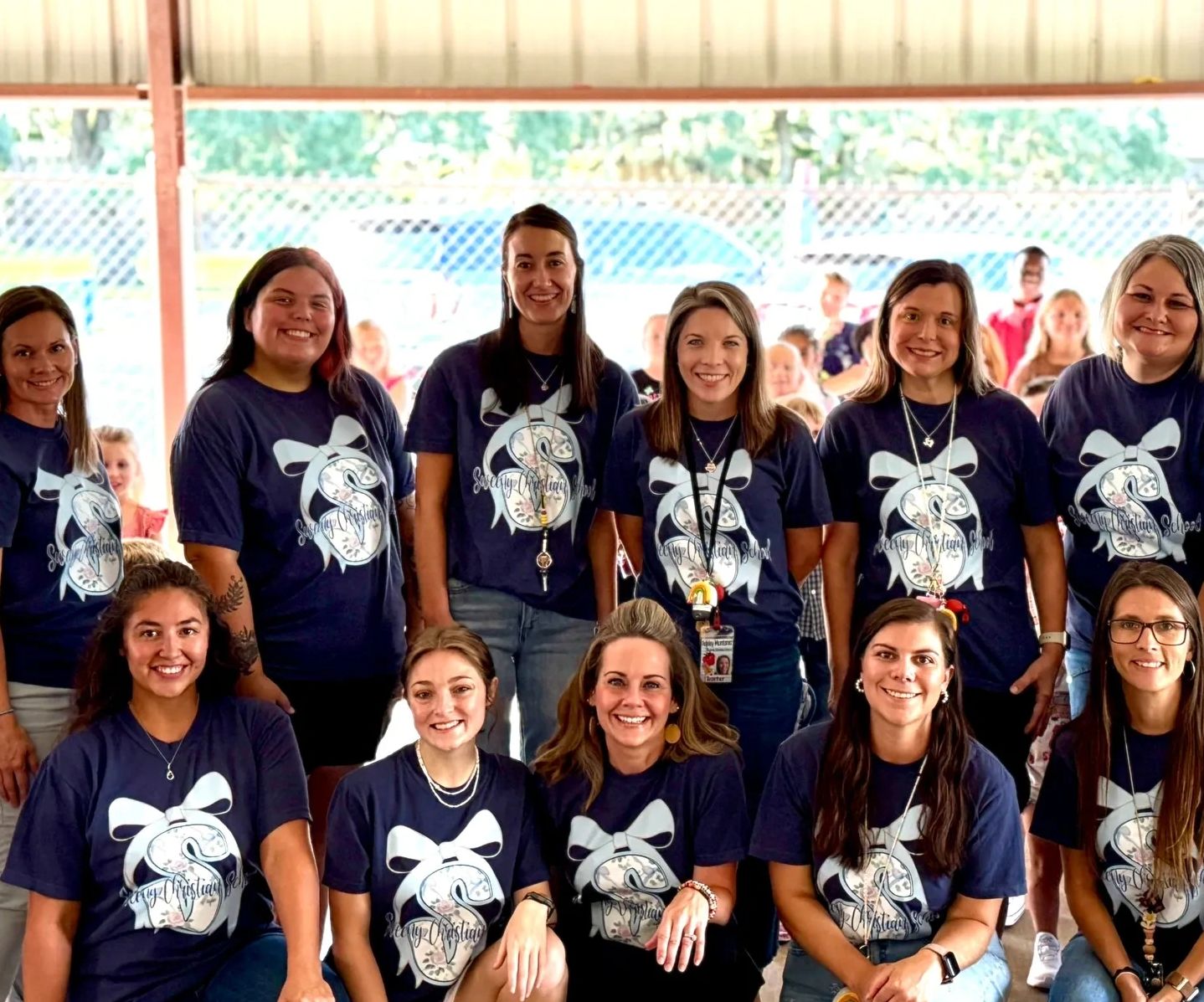 A group of smiling women in matching school t-shirts.