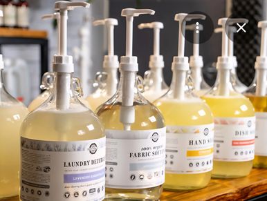 Various cleaning products with pump dispensers arranged on a wooden surface.