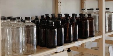 Wooden shelves with glass refill bottles for reducing single-use plastic waste.