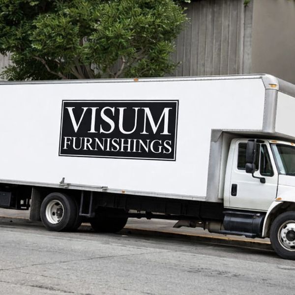 A white delivery truck with 'VISUM FURNISHINGS' logo parked on a city street.