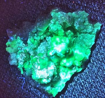 Glowing green mineral or rock under UV light on textured surface.