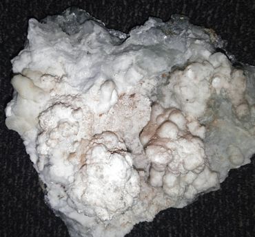 Close-up of a white, textured mineral or rock specimen with bumpy formations.