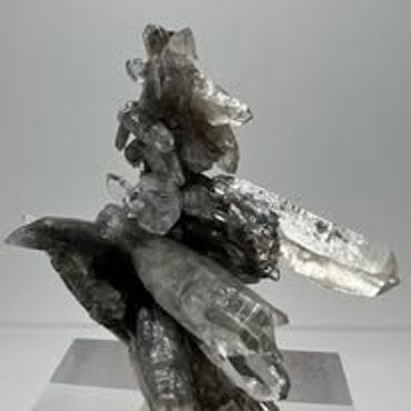 Cluster of clear quartz crystals on display stand.