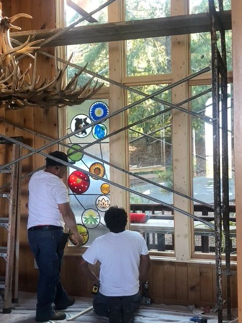 two men installing a stained glass window panel