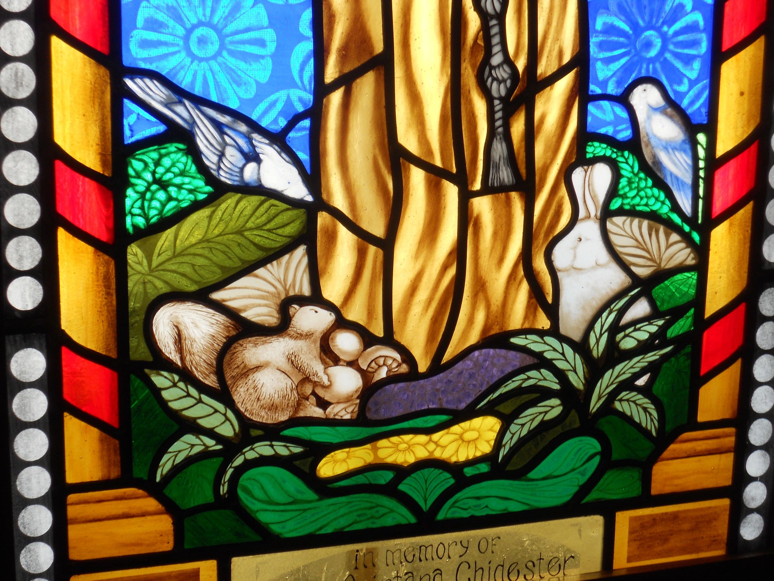 Painted glass rabbit, squirrel, and two birds at the feet of St. Francis of Assisi