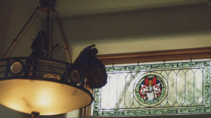transom stained glass with fancy green/black painted border. Family crest with mother goose and babi