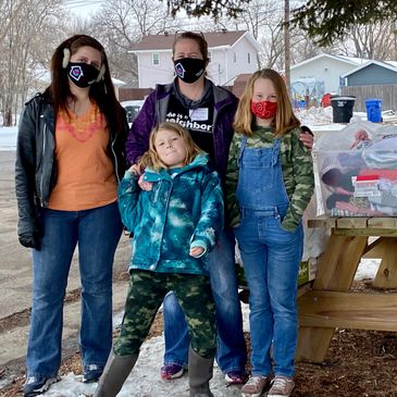A family of four wearing masks outdoors in winter.