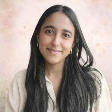 Young woman with long black hair smiling gently against a soft pastel background.