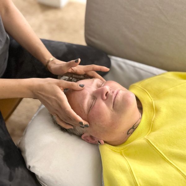 Person receiving a forehead massage while lying on a pillow.