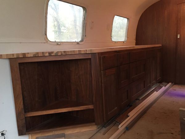 Walnut kitchen cabinets with butcher block countertop in an airstream travel trailer