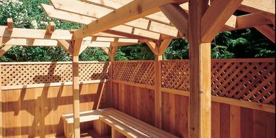 A light colored wood deck, with privacy fence, custom built seating a matching pergola.