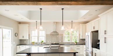 A white painted kitchen, white cabinets and grey granite countertops with 4 pendant lights.