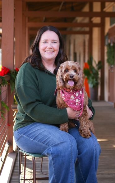Woman in green sweater holding a happy dog with a pink bandana.