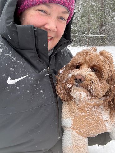 Woman and dog enjoying snowy weather outdoors.