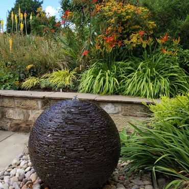 spherical slate water feature in colourful garden