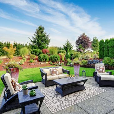 Beautifully landscaped backyard with an outdoor seating area consisting of a sofa, and chairs