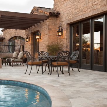 A cozy outdoor patio area with a seating arrangement of four chairs and a table beside a pool