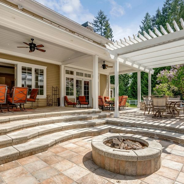 An elegant patio with comfortable outdoor furniture, a fire pit, and a pergola.
