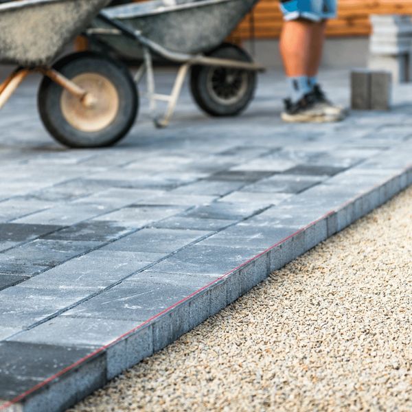 A close-up view of a newly installed gray stone pavement with a red guiding line on the edge