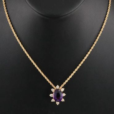 Gold necklace with a purple gemstone pendant.