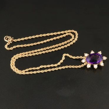 Gold chain necklace with purple gemstone pendant.